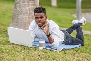 uma homem fazer a ok símbolo com dele mão em a terra usando uma computador portátil computador para trabalhos foto