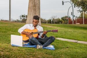 homem sentado em Relva jogando guitarra foto