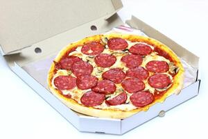 recentemente cozido pizza com linguiça dentro uma cartão caixa em uma branco fundo foto
