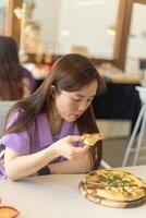 uma mulher é comendo uma pizza com dela mãos foto