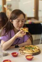 uma mulher é comendo uma pizza com dela mãos foto