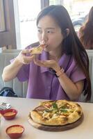 uma mulher é comendo uma pizza com dela mãos foto