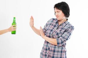 mulher de meia-idade rejeita uma mão com uma garrafa de cerveja isolada - conceito de alcoolismo feminino foto