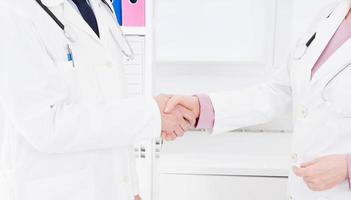 dois médicos apertam as mãos no escritório. seguro médico. conceito de saúde. copie o espaço foto