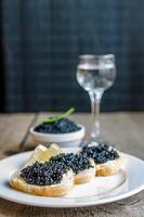 sanduíches com caviar preto e copo de vodka foto