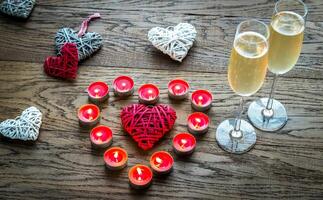 dois óculos do champanhe com queimando velas e bengala corações foto