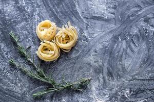 cru tagliatelle nido em a polvilhado com farinha Preto de madeira fundo foto