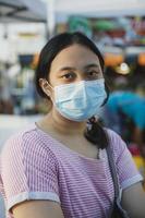 jovem asiática usando máscara protetora em pé ao ar livre foto