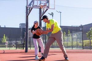 uma feliz pai e adolescente filha jogando basquetebol lado de fora às tribunal. foto