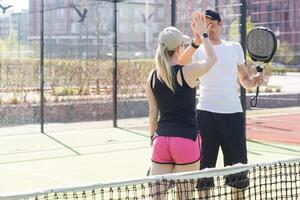 Esportes casal com padel raquetes posando em tênis quadra foto