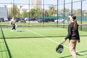 jovem meninas jogando padel em uma ensolarado dia foto