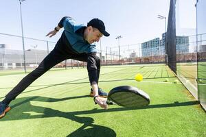 homem jogando padel dentro uma verde Relva padel quadra interior atrás a internet foto