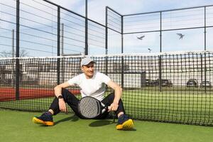 europeu homem segurando padel raquete dentro mão e pronto para Retorna bola enquanto jogando dentro quadra foto