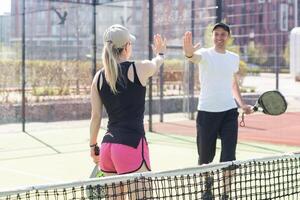 esportivo fino mulher com raquete jogando padel dentro tribunal. Visão a partir de a costas foto