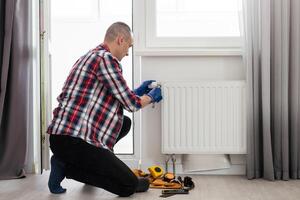 reparar aquecimento radiador fechar-se. homem reparação radiador com chave inglesa. removendo ar a partir de a radiador. foto