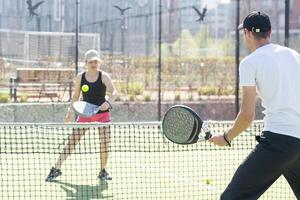 jovem desportivo mulher e homem jogando padel juntos em mesmo equipe foto