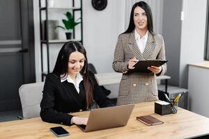 ligar Centro agente com fone de ouvido trabalhando em Apoio, suporte linha direta dentro moderno escritório. dois jovem atraente mulheres estão trabalhando dentro a escritório foto