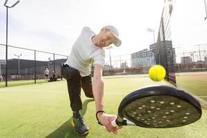 europeu homem segurando padel raquete dentro mão e pronto para Retorna bola enquanto jogando dentro quadra foto