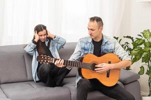 pequeno filha e dela pai jogando guitarra às casa foto