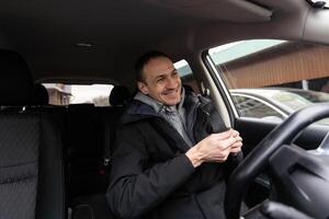 alegre indiano homem dirigindo carro, tiro a partir de painel, indo em viagem durante verão férias, cópia de espaço. feliz Oriente médio cara dentro casual equipamento e óculos dirigindo dele marca Novo agradável carro foto