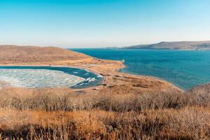 a costa do a mar do Japão com colinas e pedras. a extensões do a mar do Japão e Está costa com colinas este estão coberto com seco grama. foto