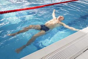 uma pensionista do 70 anos descansos e nada dentro a piscina dentro uma limpar, azul piscina dentro a fresco ar em período de férias. foto