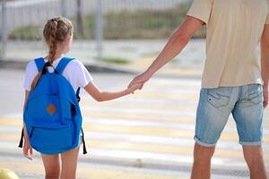 pai e filha Cruz a pedestre cruzando. costas para escola. criança e Papai ir para escola foto