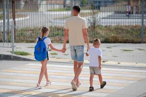 pai e filha com filho Cruz a pedestre cruzando. costas para escola. crianças e Papai ir para escola. foto