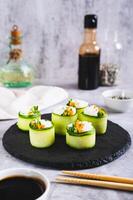 vegetal Sushi fez do arroz, pepino e cenouras em uma ardósia borda em a mesa vertical Visão foto