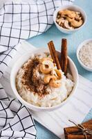 tigela com delicioso arroz pudim com canela e nozes em a mesa vertical Visão foto