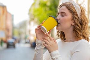 feliz jovem mulher desfrutando bebendo manhã café quente beber relaxante levando uma pausa dentro cidade rua foto