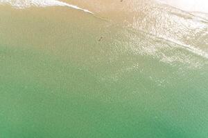 diretamente acima aéreo zangão Visão do dois pessoas dentro turquesa água em a costa do uma de praia desfrutando a verão foto