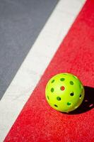 verde pickleball bola isolado em uma tribunal, Novo raquete esporte foto