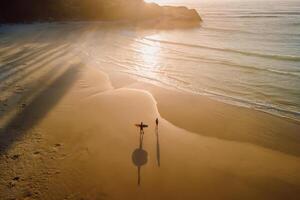 caloroso nascer do sol em oceano com sombra de surfistas e ondas. joaquina de praia dentro Brasil foto