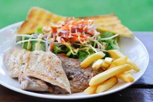 carne de porco bife e frango bife com francês fritas ,pão e salada ou grelhado carne de porco e grelhado frango com frito batata foto