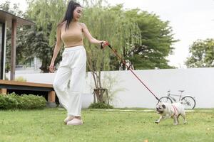 feliz ásia mulher jogando com fofa inteligente pug cachorro cachorro dentro a quintal foto