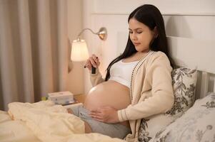 lindo grávida mulher usando lanterna em barriga para estimular uma Bêbês desenvolvimento, fertilidade infertilidade tratamento, fertilização in vitro, futuro maternidade conceito foto