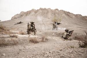 soldados dentro camuflar uniformes visando com seus rifles pronto para fogo durante militares Operação dentro a deserto soldados Treinamento dentro uma militares Operação foto