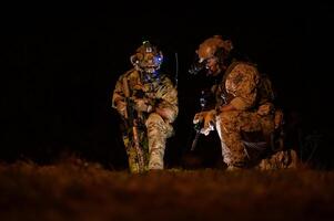 soldados dentro camuflar uniformes visando com seus rifles pronto para fogo durante militares Operação às noite, soldados Treinamento dentro uma militares Operação foto