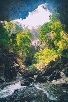 dentro a tropical floresta do kanchanaburi, da Tailândia nacional parque, cascata fluxos passar a Rocha fendas dentro frente do a caverna. foto