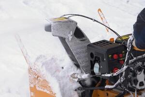 uma homem é usando uma neve ventilador para Claro neve a partir de entrada de automóveis depois de inverno tempestade, removendo neve a partir de estrada foto