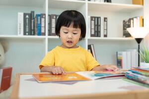 feliz ásia crianças relaxar ler livro às lar. filha e lendo uma história. aprender desenvolvimento, puericultura, rindo, Educação, narrativa, prática, Imagine, reduzir vício Móvel telefone foto