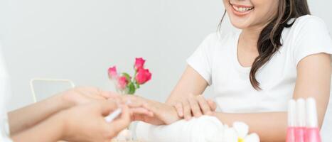 mulher recebe serviço de atendimento por manicure esteticista profissional no centro de spa. salão de beleza de unhas usa lixa de unha para tratamento de esmalte. manicure faz cliente de unha bonita. tratamento de spa para cuidados com o corpo foto