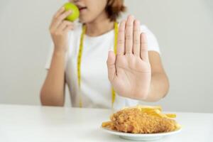 beleza fino fêmea corpo confundir francês fritas e frito frango. mulher dentro restaurante atinge peso perda objetivo para saudável vida, louco sobre magreza, fino cintura, nutricionista. dieta, corpo forma. foto