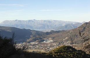 panorâmico Visão do a cidade do último a partir de a montanha dentro Montenegro. Visão do a cidade e montanhas a partir de uma altura contra a azul céu. horizontal foto