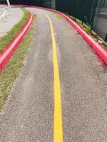 deserta asfalto ciclo caminho. demarcado dentro vermelho e amarelo com uma curva dentro perspectiva em uma ensolarado dia. foto