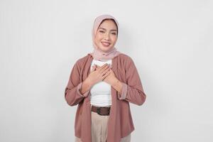 feliz atento grato jovem ásia muçulmano mulher vestindo hijab mãos em peito sorridente isolado em branco fundo. foto