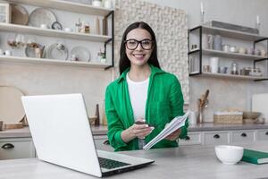 jovem lindo mulher dentro cozinha ensino on-line, professor trabalhando remotamente a partir de lar, usando computador portátil para conectados cursos, sorridente e olhando às Câmera foto