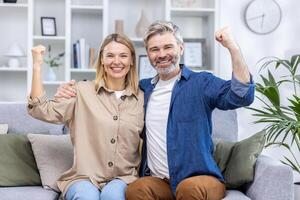 Senior família casal homem e mulher Sete sorridente e olhando às Câmera, segurando mãos acima, a comemorar vitória, sucesso e triunfo. foto