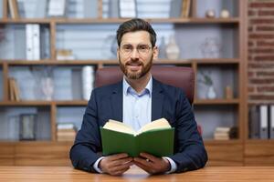 retrato do uma homem, uma pastor do uma igreja, uma religioso comunidade do vários denominações, dando dele sermão on-line. sentado dentro a escritório e olhando para dentro a Câmera, segurando uma piedosos livro. foto